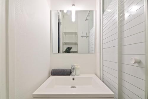 une salle de bain blanche avec un lavabo et un miroir dans l'établissement Heart of Paris - Studio - 2P - Invalides Free Netflix, à Paris