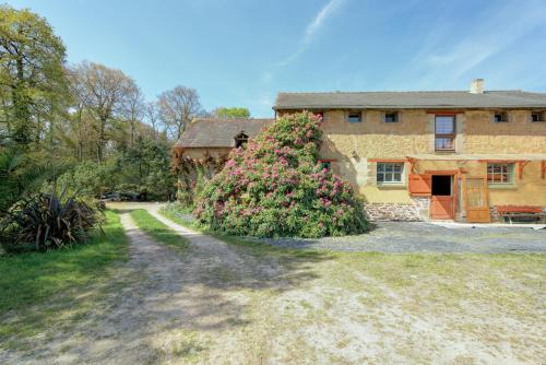 a house with a large bush of flowers in front of it at Au fournil de L'essart in Boisgervilly