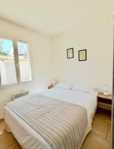 une chambre blanche avec un lit et deux fenêtres dans l'établissement DOMAINE LOU BEL AZUR - Sérénité, à Saint-Laurent-du-Var