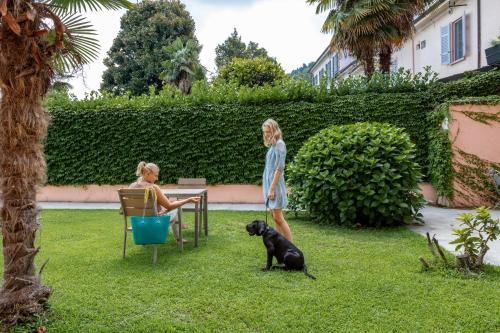 two women standing in a yard with a dog at Resort Antico Verbano in Meina