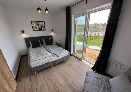 a bedroom with a bed and a large window at Apartamenty Łuska w Dębinie in Debina