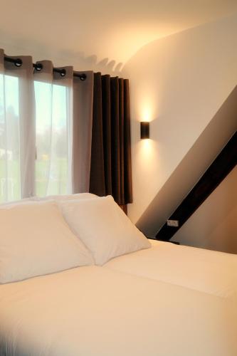 a bedroom with a white bed and a window at Hotel Restaurant des Vosges in Birkenwald