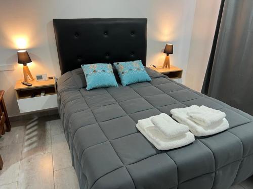 a bedroom with a large gray bed with blue pillows at Estudio Playa in Miramar