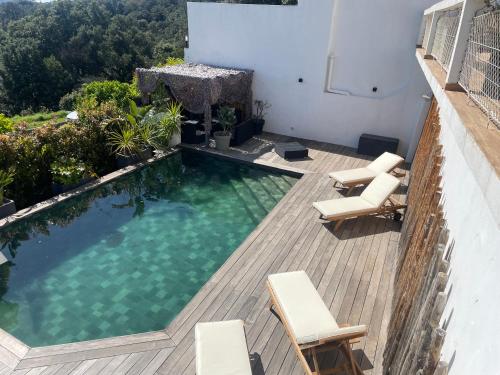- une piscine sur une terrasse avec des chaises et un bâtiment dans l'établissement Villa 