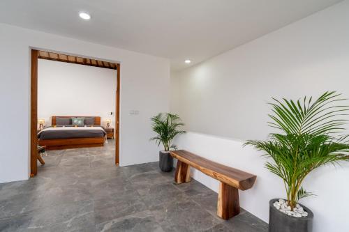 a bedroom with a bed and a bench and plants at Villa Sunset Waters in Legian