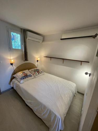 - une petite chambre avec un lit blanc et 2 lampes dans l'établissement Les Restanques vue mer violettes 1167, à Grimaud