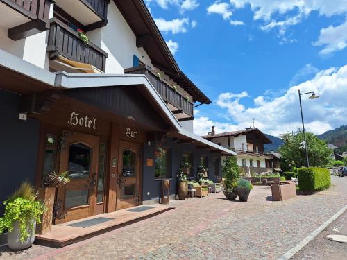 a building on a cobblestone street with a store at Hotel Nele in Ziano di Fiemme