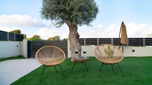 two chairs and a table with a tree and an umbrella at Villa Zachos in Pitsidia