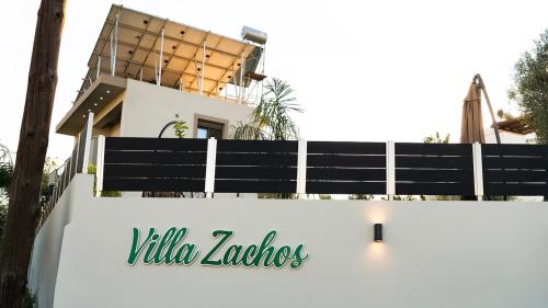 a white fence with a villa ludos sign on it at Villa Zachos in Pitsidia