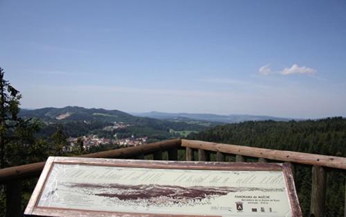 a sign on a wooden railing with a view of mountains at Gîte Le p'tit Chasseral in Maîche