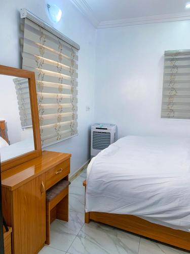 a bedroom with a bed and a dresser and a mirror at Betsy Apartments in Abuja