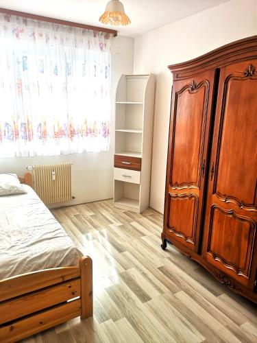 a bedroom with a large wooden cabinet and a bed at Escale Alsacienne à Sélestat in Sélestat