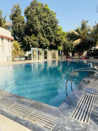 a swimming pool with blue water and two benches at Nilkanth Resort - Best Resort in Anand in Anand
