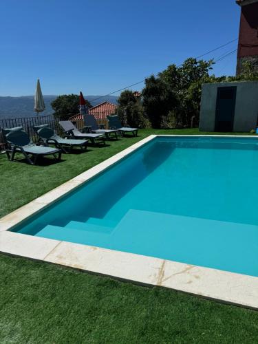 a large blue swimming pool in a yard with chairs at Casa do Pátio - Férias no Douro in Baião