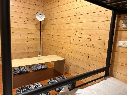 a room with a wooden wall with a bed and a lamp at B&B American Style cabin 5 minutes from the sea in Hengchun