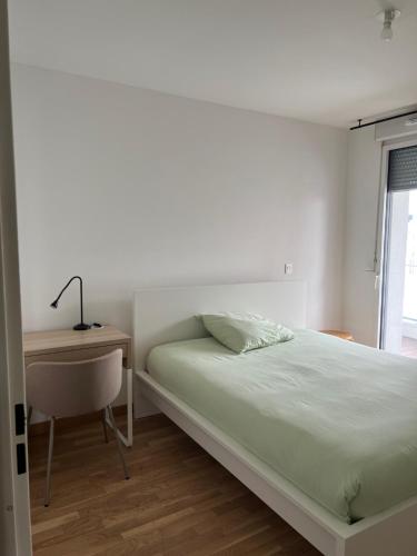 une chambre blanche avec un lit et un bureau dans l'établissement Joli T4 récent grand balcon Lyon 8 proche du métro, à Lyon