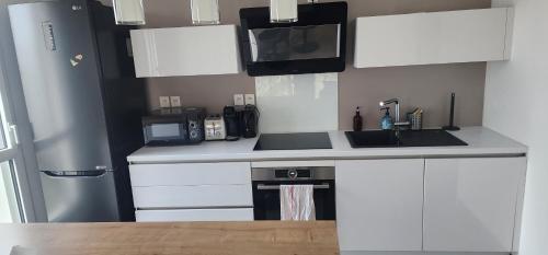 une cuisine avec des armoires blanches et un four à plaques de cuisson dans l'établissement Joli T4 récent grand balcon Lyon 8 proche du métro, à Lyon