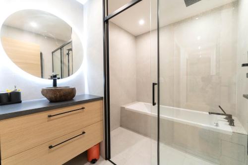 une salle de bain avec une baignoire, un lavabo et un miroir dans l'établissement Magnifique appartement avec piscine et jardin, à Nice