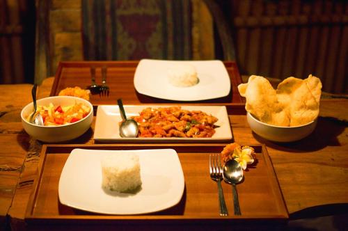 a wooden table with plates of food and bowls of food at Temple Retreat Rumah Cantik in Banjar