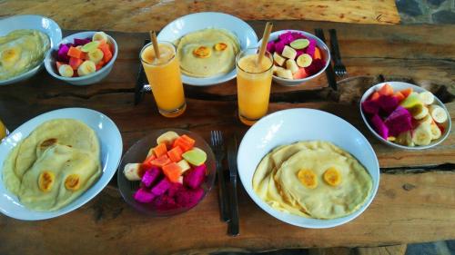 a table with plates of food and bowls of fruit at Temple Retreat Rumah Cantik in Banjar