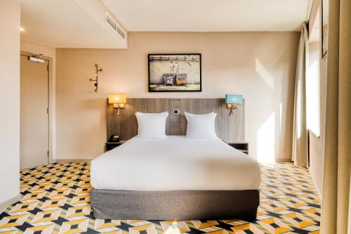 a large white bed in a room with two lamps at ALMA Grand Place Hotel in Brussels