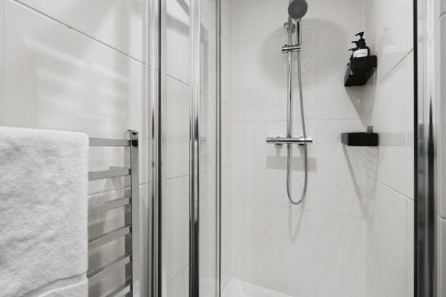 a shower with a glass door next to a towel at Large 3 bedrm apartment in heart of Theatre Land in London