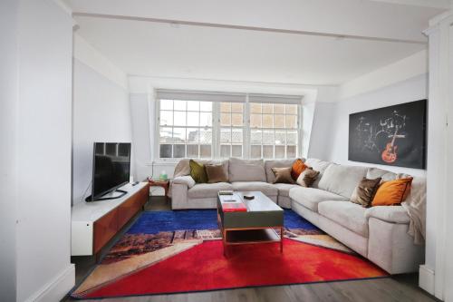 a living room with a couch and a tv at Large 3 bedrm apartment in heart of Theatre Land in London