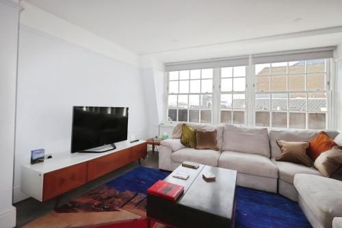 a living room with a couch and a flat screen tv at Large 3 bedrm apartment in heart of Theatre Land in London