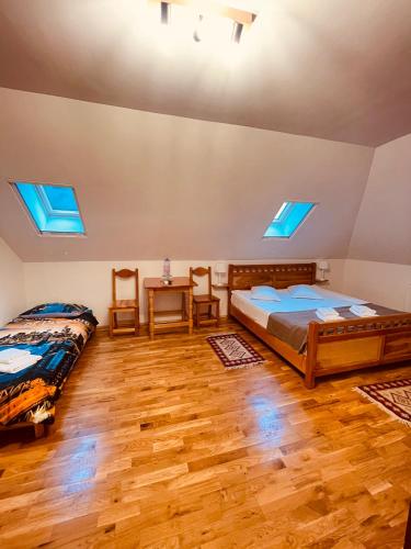 two beds in a room with wooden floors and skylights at Domeniul Bondarelului in Ocolişu Mic