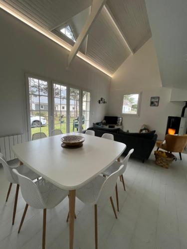 une table blanche et des chaises dans un salon dans l'établissement Villa premium 150m de la plage, à Barneville-Carteret