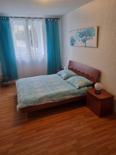 a bedroom with a bed with blue curtains and a table at Apartment Lavanda in Pješčana Uvala