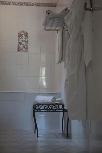 La salle de bains est pourvue d'une douche, d'un banc et de serviettes. dans l'établissement Hotel la Caravelle, à Bonifacio