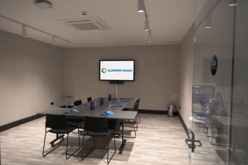 a conference room with a table and chairs and a screen at Ilunion Hacienda de Mijas in Mijas