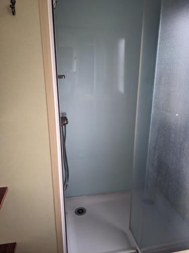 une douche avec une porte vitrée dans une salle de bain dans l'établissement Mobil-home, à Arconcey
