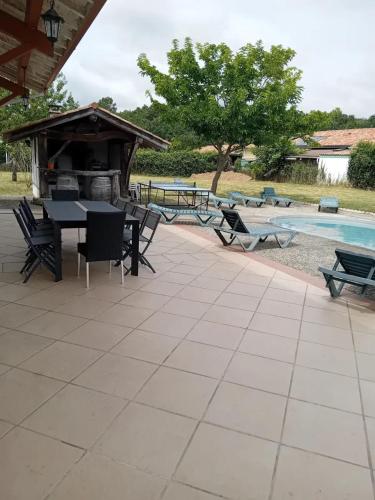 un patio avec une table et des chaises à côté d'une piscine dans l'établissement Villa confortable avec piscine privée à Sainte-Marie-de-Gosse, 180 m², à Sainte Marie de Gosse