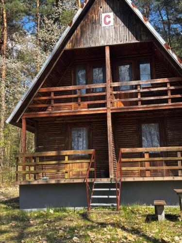 a large wooden house with a staircase in front of it at Leśna Osada Tęcza Jabłonowiec in Jabłonowiec