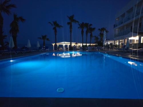a large blue swimming pool at night with palm trees at Souli Beach Hotel in Polis Chrysochous