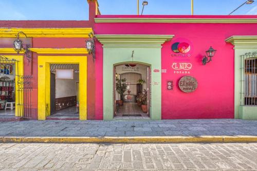 a pink and yellow building on a street at Capital O El Nito Posada in Oaxaca City