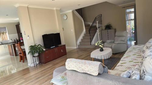 a living room with a couch and a tv at Stylish 5 Bedroom Property in Auckland