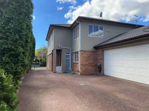 a house with a white garage and a driveway at Stylish 5 Bedroom Property in Auckland