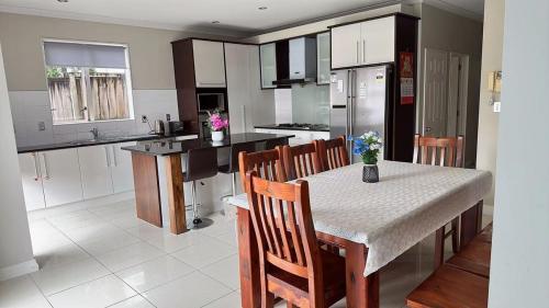 a kitchen with a table and chairs and a kitchen with white cabinets at Stylish 5 Bedroom Property in Auckland