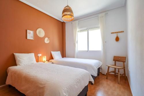 two beds in a room with orange walls and a window at Casa Joek in Los Alcázares