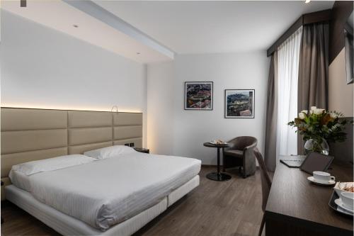 a bedroom with a white bed and a desk and a table at Hotel Minerva in Arezzo