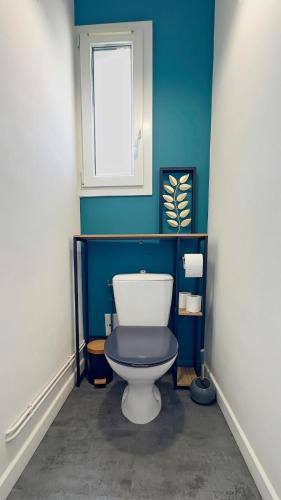 a bathroom with a toilet with a blue wall at Le Coquelicot in Dompierre-sur-Mer