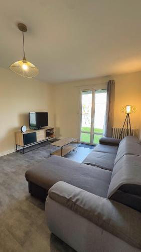 a large living room with a couch and a tv at Le Coquelicot in Dompierre-sur-Mer