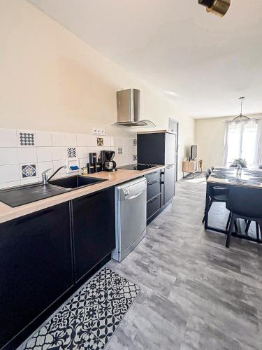 a large kitchen with a sink and a table at Le Coquelicot in Dompierre-sur-Mer