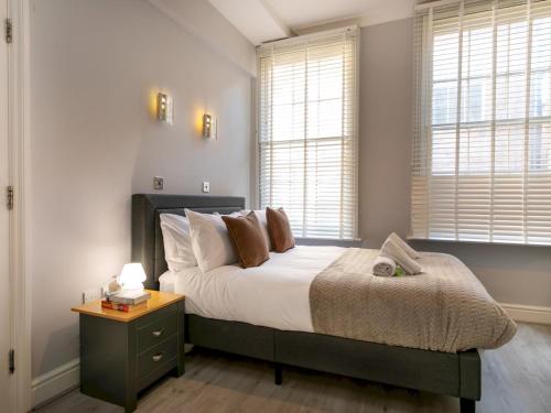 a bedroom with a bed with a nightstand and windows at Central Gem Plush Beds -Walk to Attractions - Pass the Keys in Nottingham