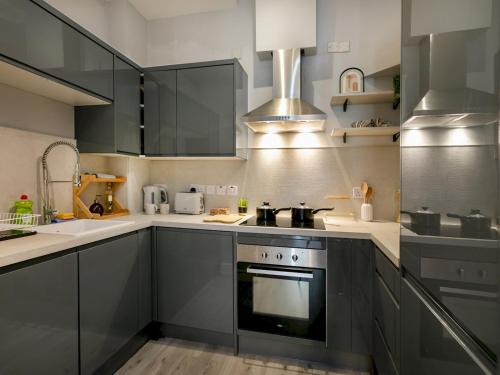 a kitchen with gray cabinets and a stove at Central Gem Plush Beds -Walk to Attractions - Pass the Keys in Nottingham