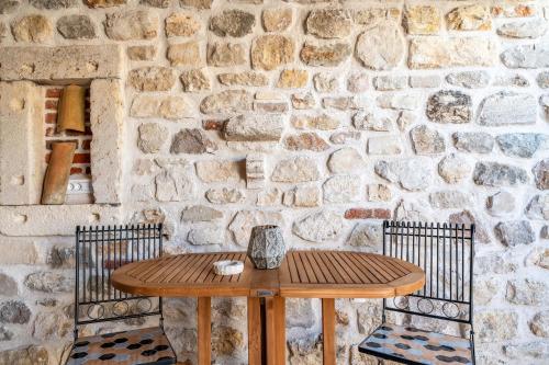 a wooden table and two chairs in front of a stone wall at Roman style stone Villa Lux Solis in Nin
