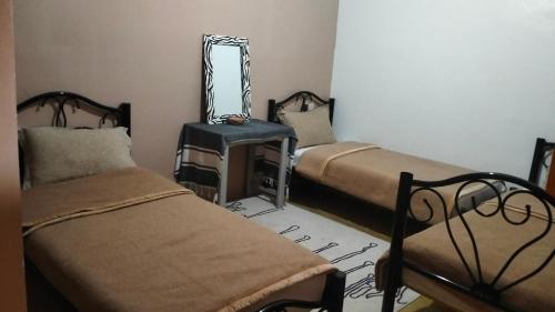 a room with two beds and a mirror on the wall at Kasbat Taslit chez l'habitant in Tajda